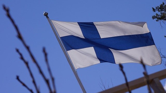 Finnish flag waving against clear blue sky symbolizing Finnish happiness and culture
