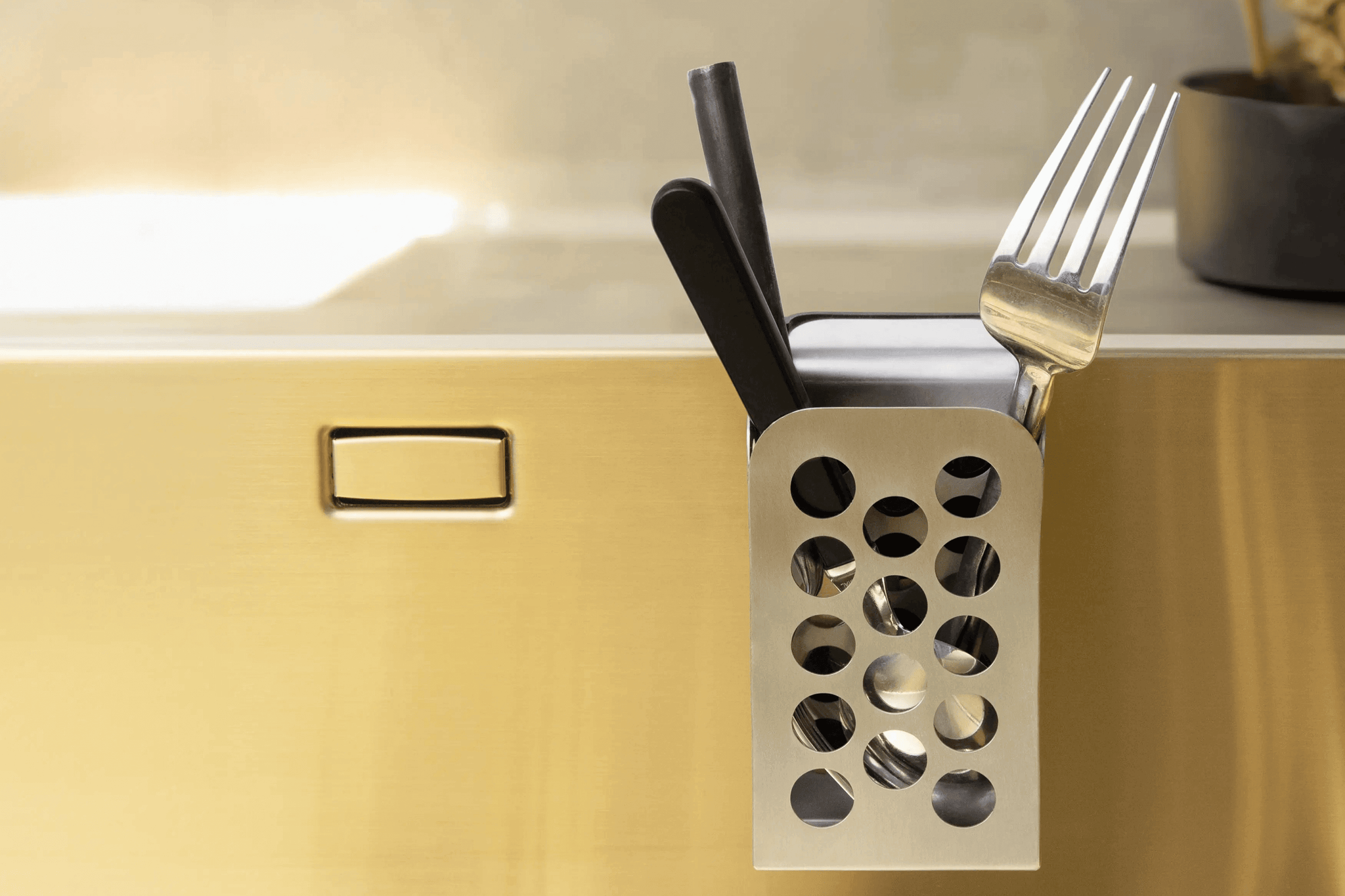 Stainless steel cutlery caddy holding forks and knives on kitchen countertop