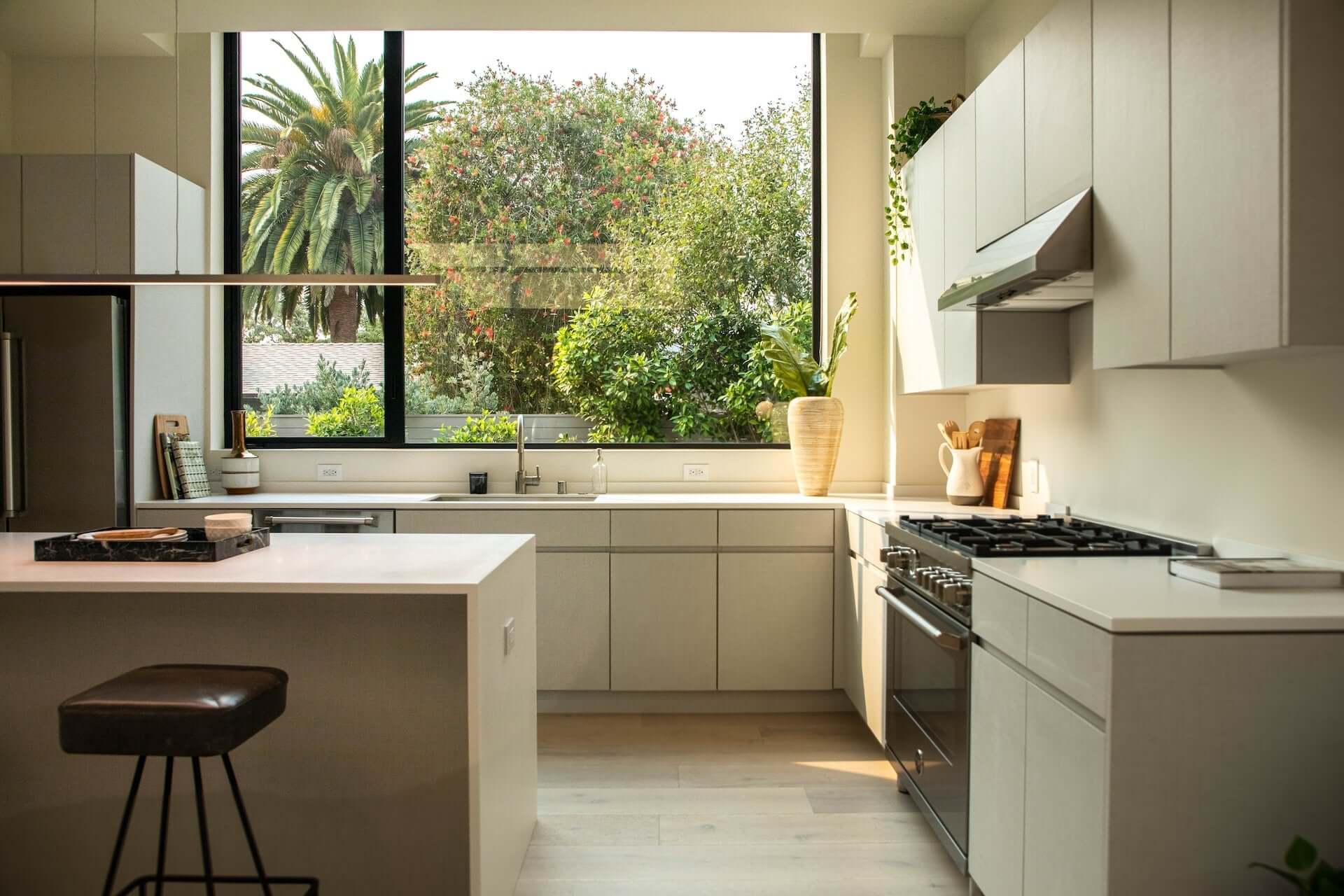 Modern bright kitchen interior with minimalist cabinetry and large window view of greenery