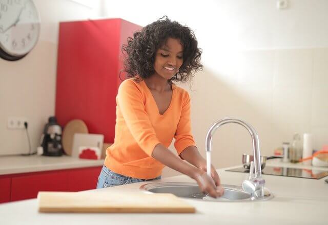 woman washing hands in kitchen sink demonstrating quick cleaning tips