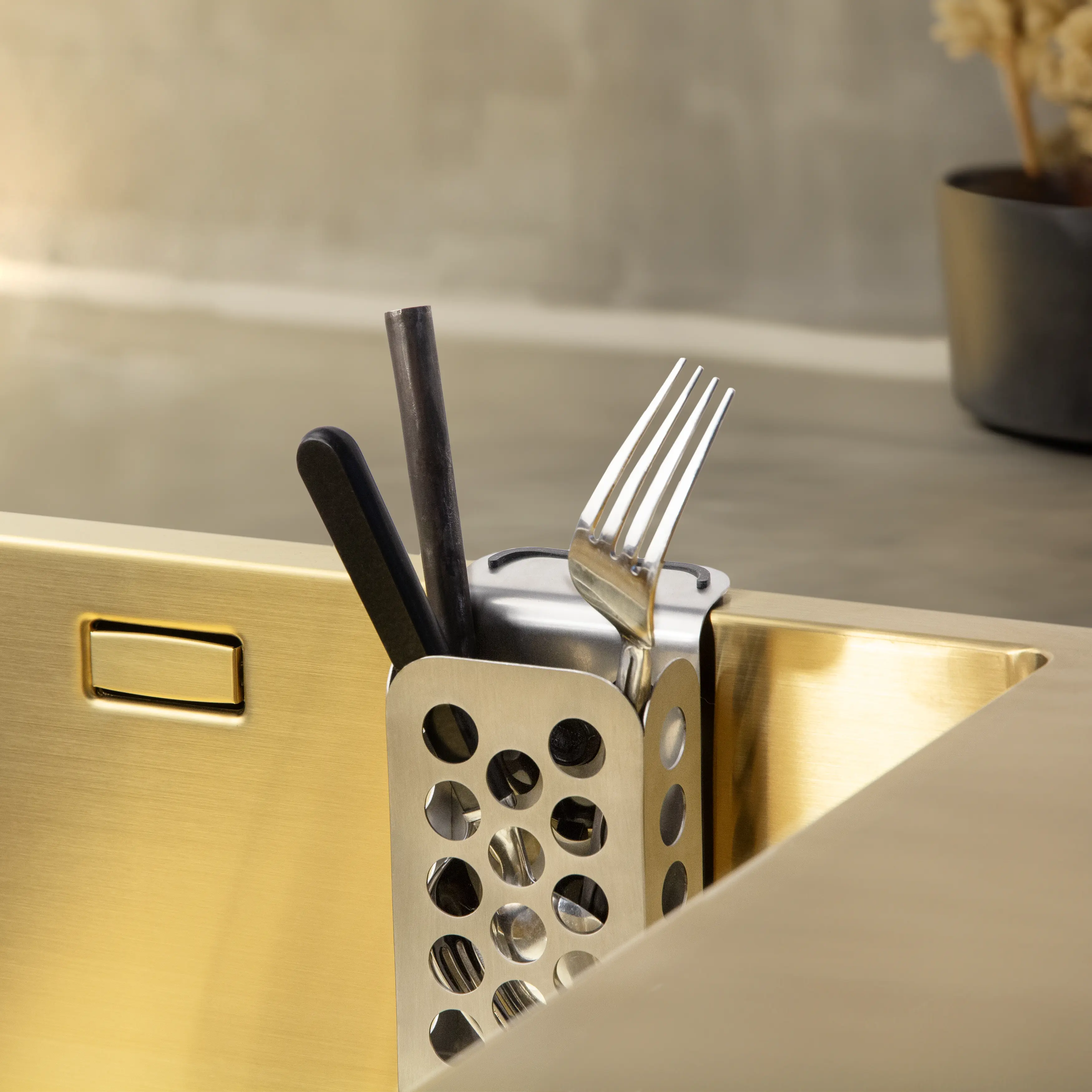 Sleek stainless steel cutlery caddy organizing utensils in sink.